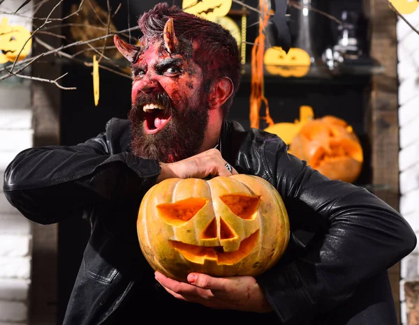 Demon with horns and mad face holds jack o lantern. — Stock Photo, Image