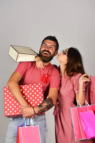 Birbirine aşık çiftler alışveriş torbaları, kucaklaşmalar ve öpücükler taşır. — Stok fotoğraf
