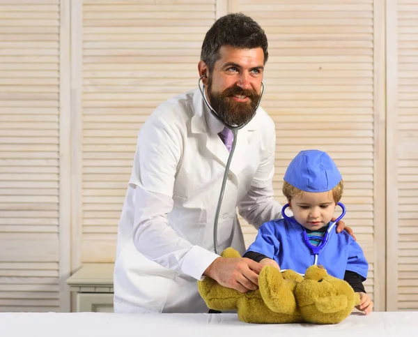 Hombre y niño sostienen estetoscopios sobre fondo de madera . — Foto de Stock