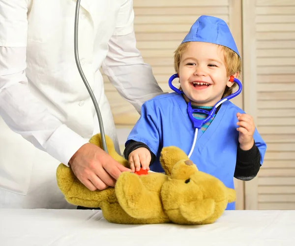 Kleine Assistentin untersucht Teddybär. Männliche Hand hält Bären — Stockfoto