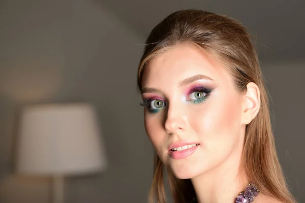 Menina no quarto com paredes cinzentas usando maquiagem colorida — Fotografia de Stock