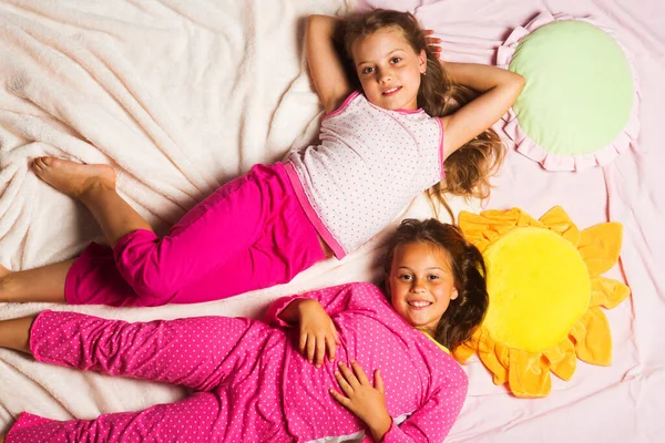 Écolières ayant pyjama partie avec des oreillers drôles. Photo De Stock