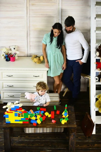 Föräldrar och son med nyfiken ansikte leka med leksaker — Stockfoto