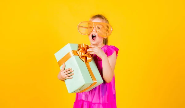 gift of surprise. its shopping time. small girl hold present box. little kid with gift box. happy birthday party. childhood happiness. lets celebrate holiday. child in summer day on yellow background