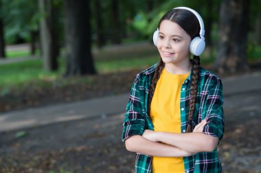 Harika seyahat teknolojisi. Küçük kız ormanda müzik dinler. Küçük çocuk sıradan bir şekilde kulaklık takıyor. Yeni teknoloji. Kablosuz teknoloji. Modern hayat. Senkronize ol ve git, boşluğu kopyala