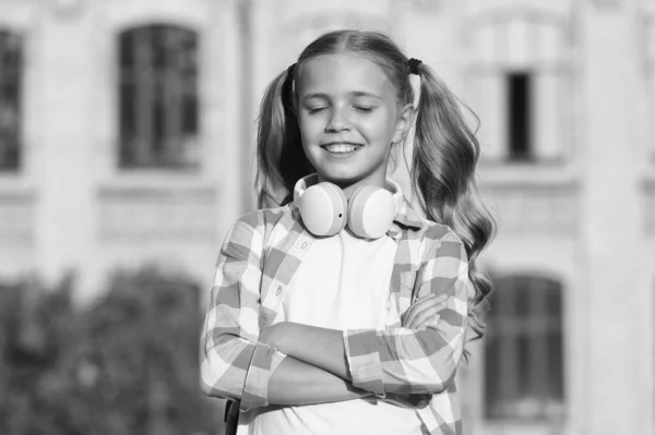 Veselý milovník hudby. Holčička nosí kostkovanou košili. dítě se sluchátky při západu slunce. na jaře a v létě. Šťastné dětství. e-learning s ebook. moderní technologie — Stock fotografie