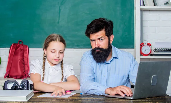 En skäggig pedagog som undervisar i informatik. Studera online. Hemundervisning med far. Hitta en kompis som kan hjälpa dig plugga. Privatlektion. Lärare och skolflicka med laptop. Studera modern teknik — Stockfoto