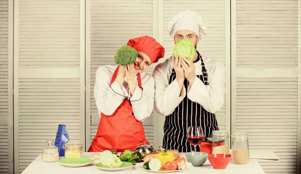 Couple cooking healthy vegetarian meal. Vegetarian family. Vegetarian nutrition and vegetable diet. Diet on their mind. Couple cooks hold cabbage and broccoli in front of face. Healthy food concept