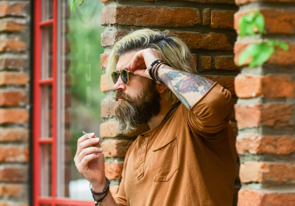 Cool mec relaxant. J'ai fait une pause-fumée. Hipster fumeur irlandaise pub arrière-plan d'entrée. Fumer à l'extérieur. Homme mature à la mode avec cigarette. L'habitude de fumer. Brutal gars lunettes de soleil fumer tabac — Photo