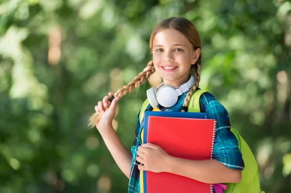 Ragazza con le treccine. Ragazza felice torna a scuola. Ragazzina tenere borsa libro naturale all'aperto. Shopping per l'essenziale della scuola. Giorno della conoscenza. Avviamento. 1 settembre. L'estate è finita — Foto Stock