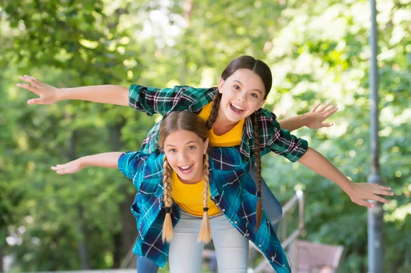 Vuela conmigo. retrato de hermanas felices. Niñas con camisa. Dos chicas hipster divertidas jóvenes en ropa de verano de moda. niños despreocupados posando al aire libre. Modelos positivos. Traje casual hipsters — Foto de Stock