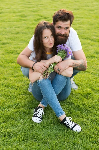 Feliz día de las mujeres. Hombre barbudo dar flores a la mujer sexy. Pareja feliz enamorada en la hierba verde. Celebrando el día de las mujeres. Tienda de flores. Vacaciones internacionales para mujeres. Día de la mujer el 8 de marzo — Foto de Stock