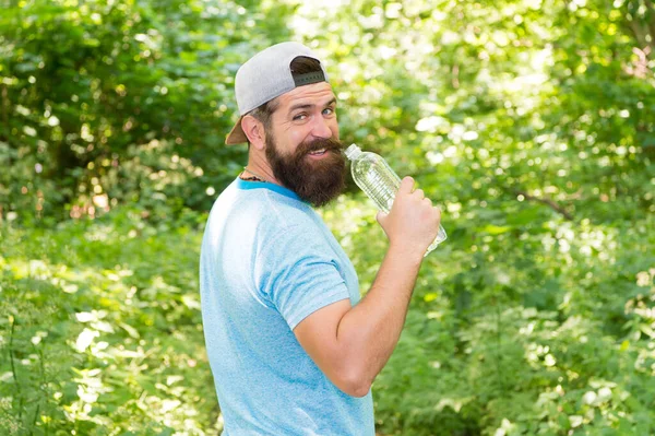 Återfukta eller dö. brutal hipster i skogen. upptäcka nya platser. Dags för picknick. Killen dricker vatten. mogen skäggig man i mössa. sommarcampingsemester. man hipster vandring. man känner törst — Stockfoto