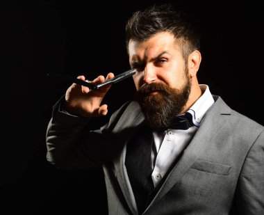 Uzun sakallı adam jileti gözüne yakın tutuyor.