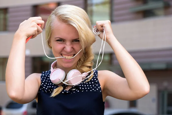 Jovencita con auriculares modernos sobre fondo urbano, desenfocada . — Foto de Stock