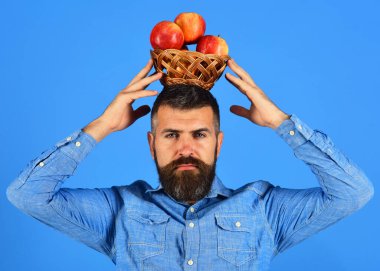 Adam evde yetişen hasatı sunuyor. Sakallı adam hasır kaseyi tutuyor.