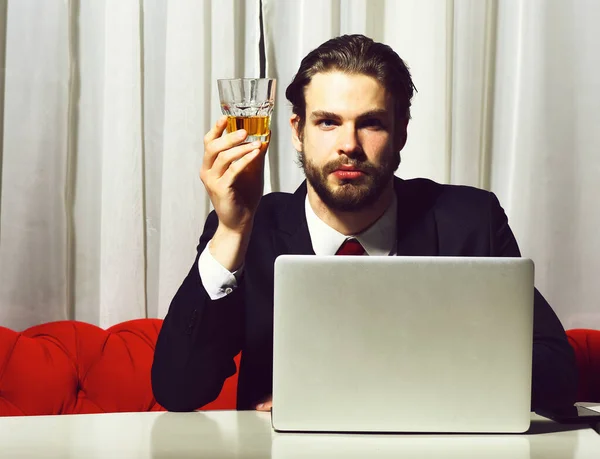 Szakállas férfi, üzletember kezében üveg whiskey működik a laptopon — Stock Fotó
