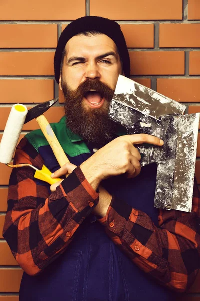 Бородатый строитель, держащий различные строительные инструменты со счастливым лицом — стоковое фото
