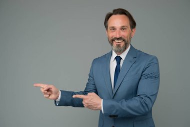 Gülümseyen adam iyi görünümlü işadamı fotokopi alanını gösterir, yönünü seçer.