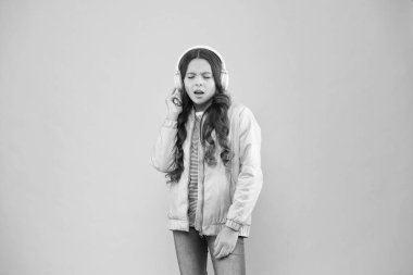 Tam eğlence. Akorda eşlik ediyorum. Mutlu çocuk müzik dinlemekten zevk alır. Küçük kız pembe kulaklık takıyor. Sesin tadını çıkar. Ses titreşimleri. Müzik ve teknoloji. Ses sesi