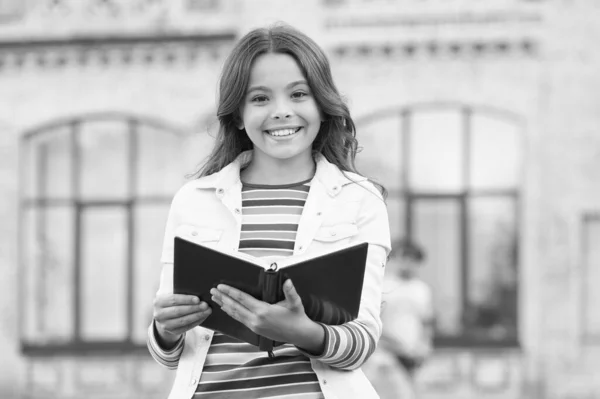 Ať vaše dítě zjistí fakta o encyklopedii. Šťastná dívka drží encyklopedii venku. Čtu encyklopedickou knihu. Znalosti a informace. Škola a vzdělání. Dětská encyklopedie. Knihovna — Stock fotografie