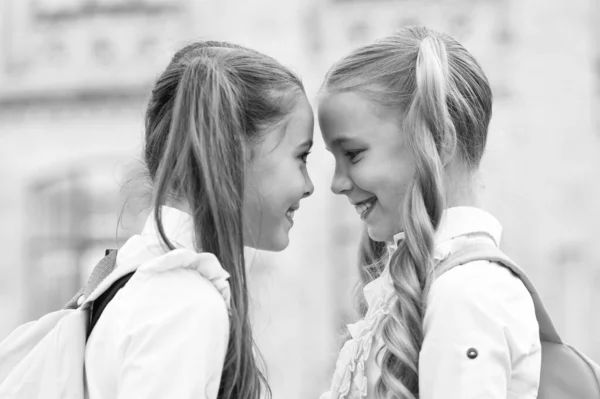 Amigos del alma gemela. Las colegialas pequeñas usan uniforme escolar. Lindas colegialas con largas colas de caballo con aspecto encantador. Fin del año escolar. Alegre colegialas inteligentes. Colegialas felices al aire libre — Foto de Stock