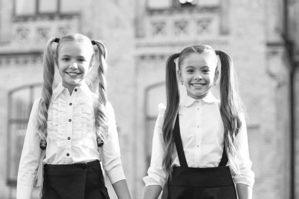 Fim do ano letivo. É uma sorte conhecer-nos. Alunas inteligentes e alegres. Boas alunas ao ar livre. Pequenas alunas usam uniforme escolar. Estudantes bonitos com rabo de cavalo longo olhar encantador — Fotografia de Stock