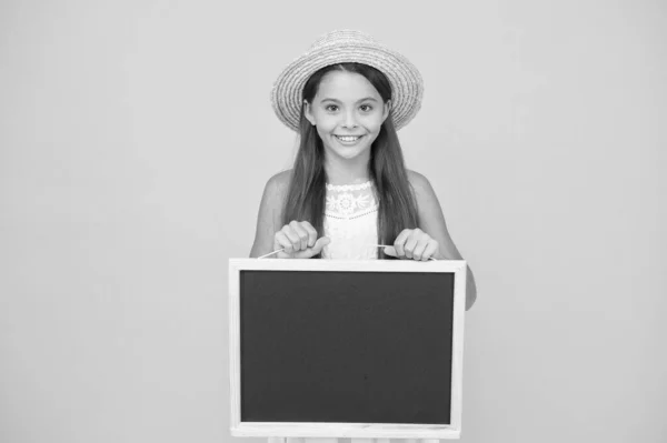 Anúncio e informação. menina elegante tropical com bordo. espaço de cópia. menina feliz em chapéu de palha no fundo amarelo. Acessórios de viajante menina romântica. miúdo retro expressar surpresa. Bonito e elegante — Fotografia de Stock