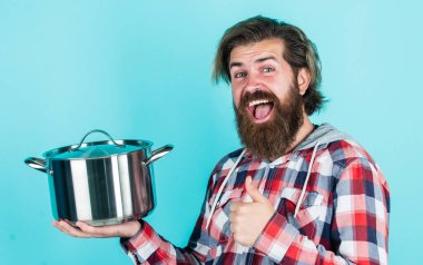 Başparmağını kaldır. Profesyonel aşçı. Sakallı adam mutfak tepsisini tut. Tencereli vahşi hippi yemekleri. Hizmetçi koca, tencerede yemek yapıyor. Kareli gömlekli olgun bir aşçı. Evde yemek hazırla.