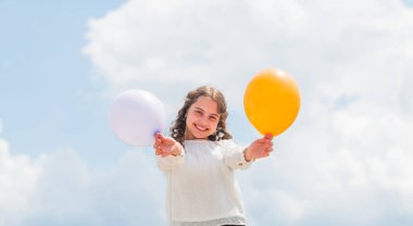 Keyif alıyorum. Eğlenmene bak. Özgürlük. Yaz tatili kutlaması. Uluslararası Çocuk Günü. Mavi gökyüzü arka planında renkli balonları olan mutlu çocuk. pozitif duyguları ifade et