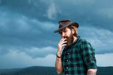 Sakallı adam. Teksas vahşi kovboyu. Bıyıklı vahşi hippi şapkalı. Manken gündelik batı kıyafetleri giyer. Erkek güzellik standardı. Çok modaya uygun görünüyorsun. Kendine güvenen ve yakışıklı bir adam. Country müziği