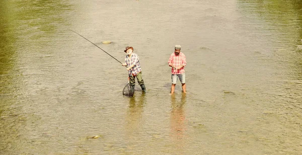 一个团队。父亲和儿子钓鱼。冒险。户外的娱乐和休闲。业余爱好和体育活动。鳟鱼饵两个快乐的渔夫带着钓竿和渔网。大游戏钓鱼。男性友谊 — 图库照片