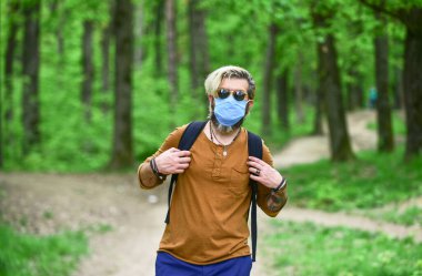 Hippi hava kirlenmesinden ya da koronavirüsten koruyor. Virüs enfeksiyonu. Enfeksiyonu durdur Kilitleme kısıtlamalarından yavaşça çıkın. Parkta yürü. Enfeksiyon kapma. İnsan yüz maskesi takarak doğanın tadını çıkarır