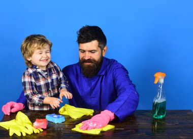 Babası olan bir çocuk sarı paçavralarla ahşap masayı siliyor..