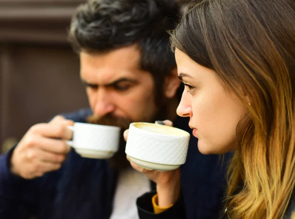 Девушка и бородатый парень пьют кофе на фоне коричневой террасы. — стоковое фото