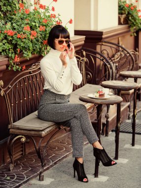 Rahatla ve kahve molası ver. Çekici, zarif bir esmer kadın boş zamanlarını kafenin terasında geçirir. Seni duyduğuma sevindim. Boş zaman konsepti. Akıllı telefonlu şık bir bayan. Keyifli zaman ve boş zaman