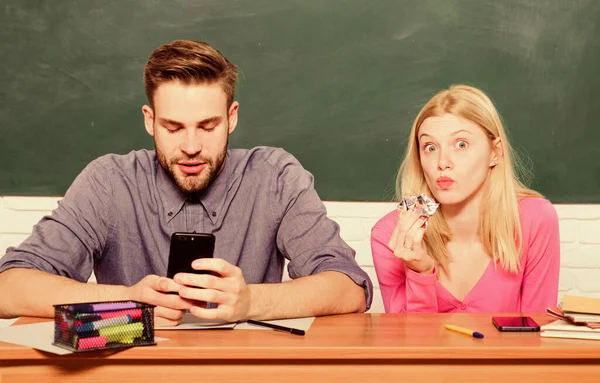 A divertir-se na faculdade. A aproveitar o tempo na faculdade. Guy e garota despreocupados sentam-se na mesa na sala de aula. Estudar na faculdade ou na universidade. Amigos estudantes estudando universidade. Diversão universitária. Educação moderna — Fotografia de Stock