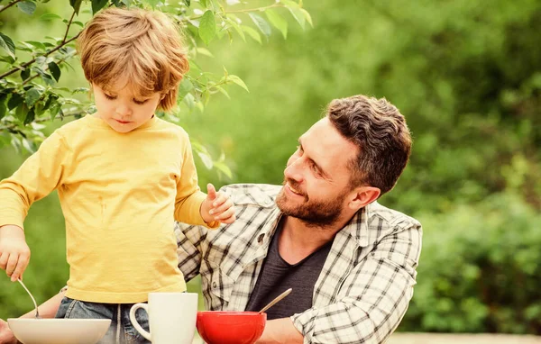 Healthy food and dieting. Childrens day. summer picnic. Morning breakfast. father and son eating outdoor. happy fathers day. Little boy with dad eat cereal. family dinner time. Happy to be a family — Stock Photo, Image