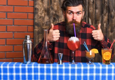 Sakallı ve neşeli yüzlü barmen camdan içer.