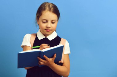 Mavi arka planda özenli yüz ifadesi olan liseli kız
