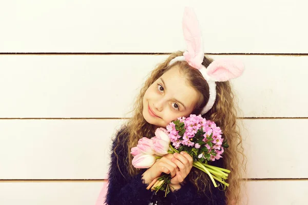 Chica feliz en orejas de conejo de Pascua con flor de tulipán rosa — Foto de Stock