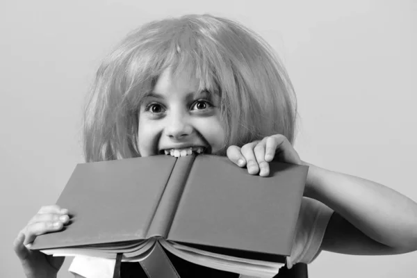 Dziewczyna gryzie dużą niebieską książkę: koncepcja edukacji — Zdjęcie stockowe