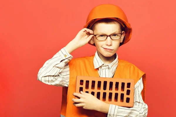 Jong schattig bouwer jongen op rode studio achtergrond — Stockfoto