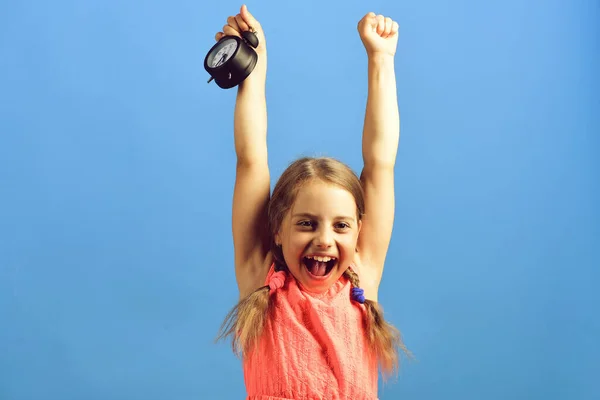 Kind im rosa Kleid mit niedlichen Zöpfen hält Wecker — Stockfoto