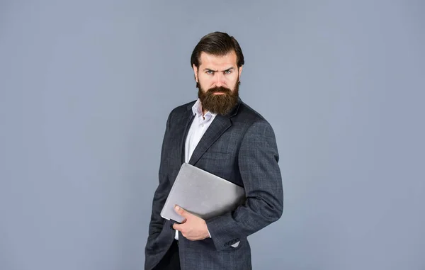 Camino a la oficina. Serio caucásico barbudo hipster con ordenador. empleado masculino que sostiene informe financiero e investiga en el espacio de coworking en el ordenador portátil. nueva tecnología en los negocios modernos mentira —  Fotos de Stock