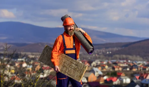 man roofer inspecting damaged roof. Qualified builder installing roof tile. construction work with roofing felt. roof industrial. Roofer contractor laying rooftop with protective helmet. sunny day