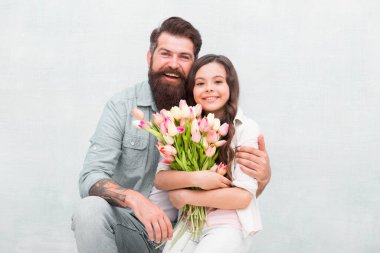 Mutlu çocuklar günü. Mutlu aile çocuk gününü kutluyor. Baba kucağında çiçeklerle küçük kızını kucaklar. Sakallı adam ve küçük çocuk. Tatil kutlaması. Uluslararası Çocuk Günü
