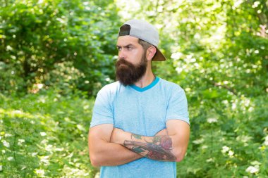 Ayaklarını sıcağa basma. Esmer sakallı adam ormanda ağaçların arkasına şapka takıyor. Vahşi esmer, sakallı adam. Sakallı, olgun bir adam. Güzel bir yaz günü. Sakallı adam kendinden emin görün.