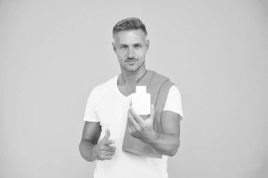 Yakışıklı, bakımlı, sağlıklı bir adam ürün öneriyor. Vücut bakımı. Ürünü sunuyorum. Tıraş olduktan sonra. Erkekler için makyaj malzemeleri. Güzellik ürünü. Olgun bir erkek vücudu. Spor ve spor. Güzellik için mallar