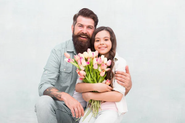 Glücklicher Kindertag. Glückliche Familie feiert Kindertag. Vater umarmt kleine Tochter mit Blumen. Bärtiger Mann und kleines Kind. Feiertagsfeier. Internationaler Kindertag — Stockfoto